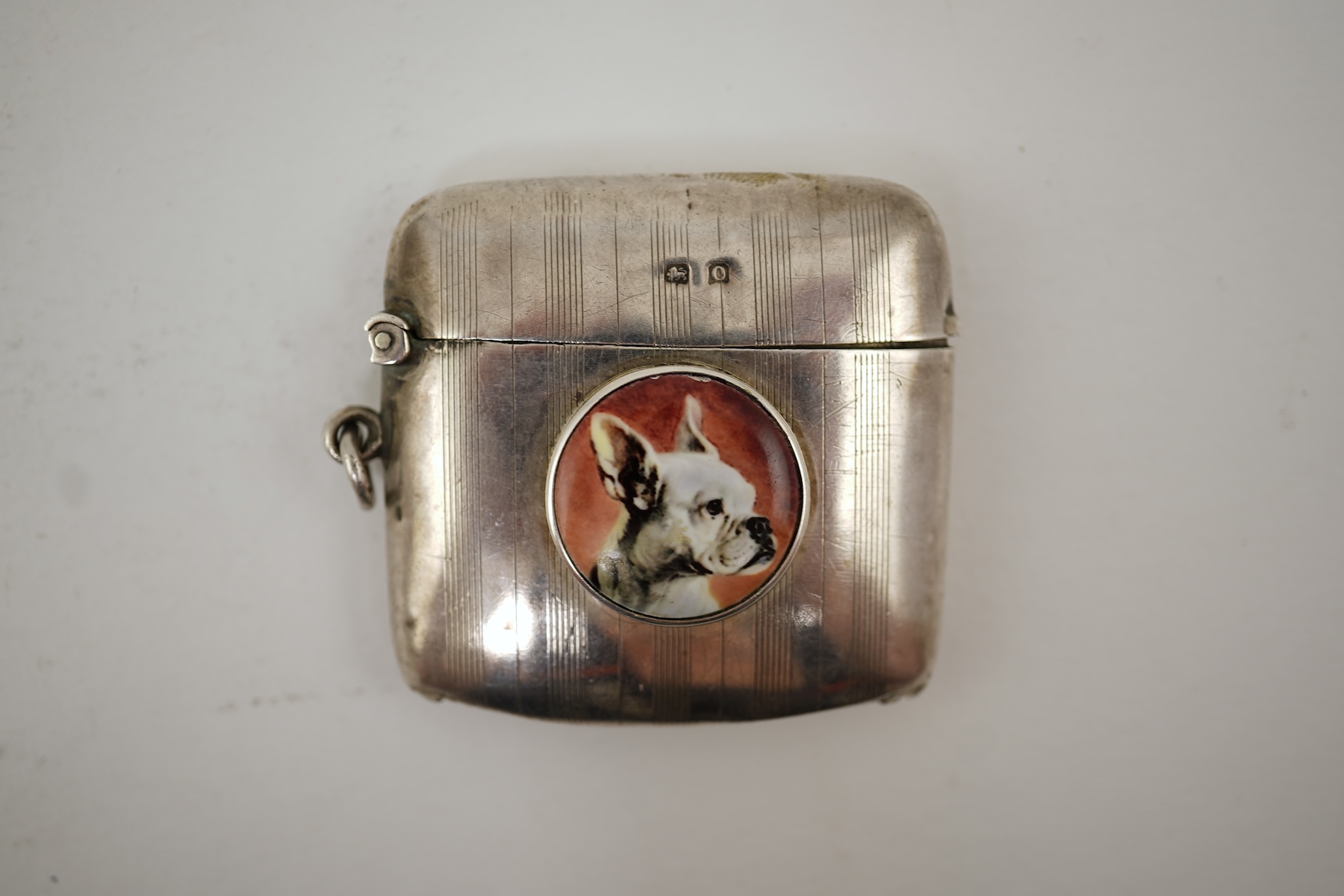 A George V silver and enamel vesta case, by Henry Hyde Aston, the inset circular enamel plaque decorated with a French bulldog